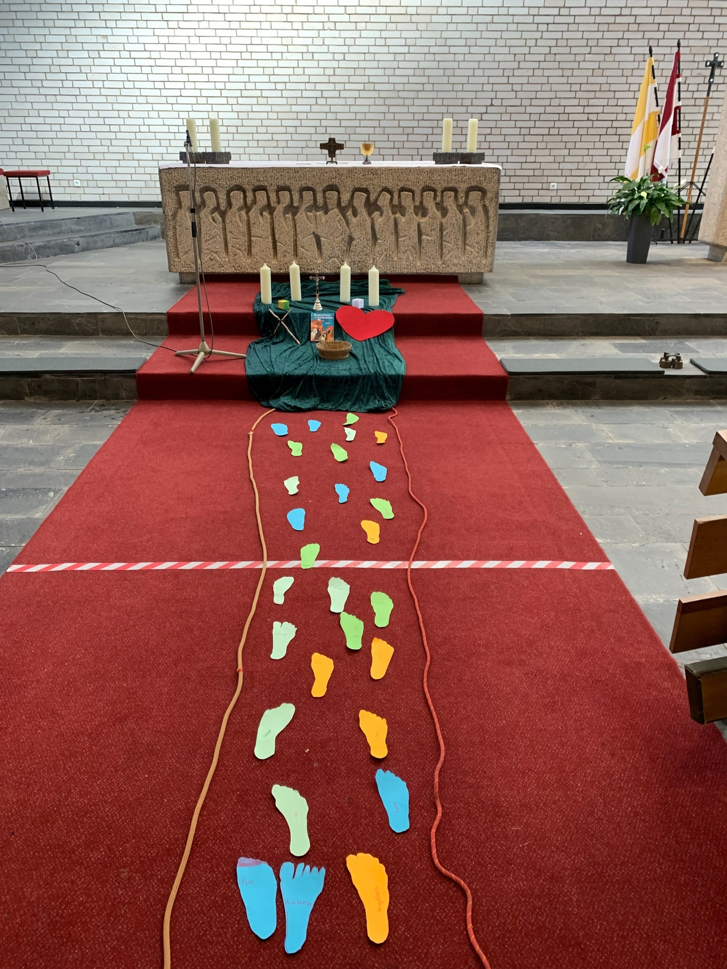 Jedes Kind hatte seinen Fuß auf ein Papier gemalt und auf den Weg zum Altar gelegt.